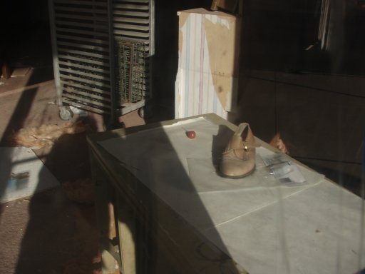 A lollypop, and a left shoe sit on a table inside an abandoned shop.