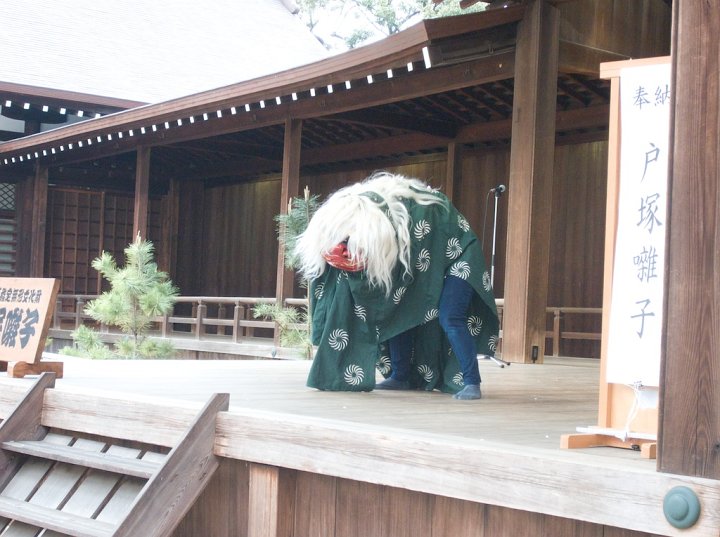A Japanese dancing lion bows to the audience after completing a lion dance. The lion dances to flute and drum music while driving off evil spirits and dispensing good luck. This lion dances at Yasukuni Shine, Tokyo, Japan.