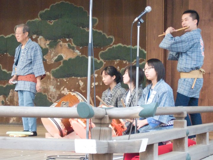 Flute and drum musicians play for a lion dance at Yasukuni Shrine, Tokyo, Japan. The lion races, leaps and lands to the beat of drums.