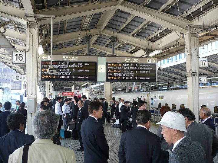 Businessmen wait on a platform for their Shinkansen to arrive. Everyday the high speed train transports more than 900,000 people nationwide