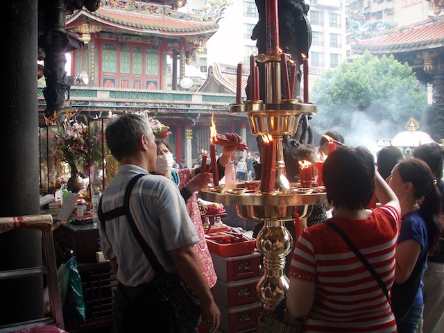 Worshippers show respect to ancestors and idols with lighted candles at Lungshan Temple in Taipei, Taiwan.