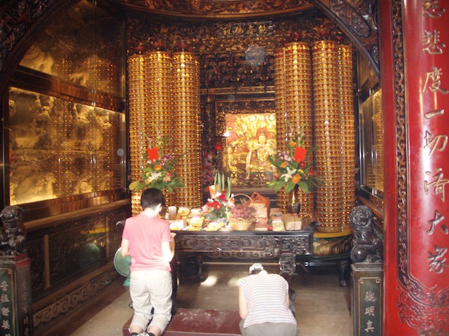 Women kneel before one of the many idlols in the temple for Matsu. Matsu is the most powerful of the idols at the temple in the Dajia District of Taichun, Taiwan.