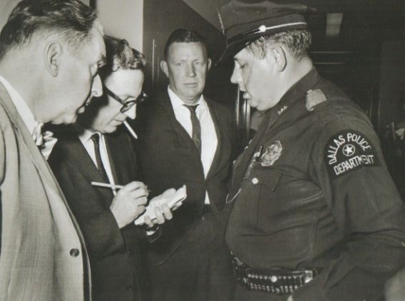 Reporters interview an officer who apprehended Lee Harvey Oswald in the Texas Theatre after he killed Dallas Police Officer J. D. Tippit.