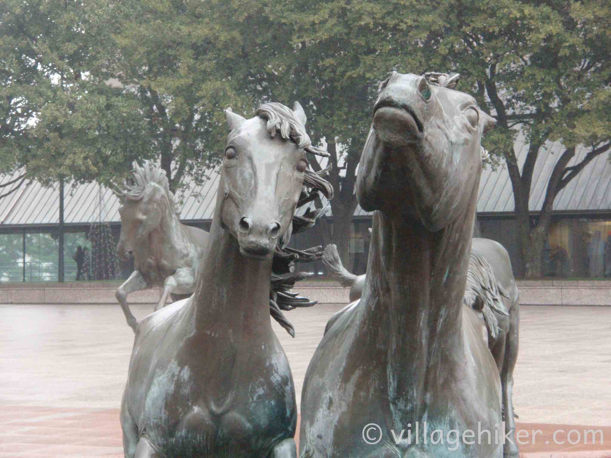 bronze mustangs splash through the fountain in a heavy rain.