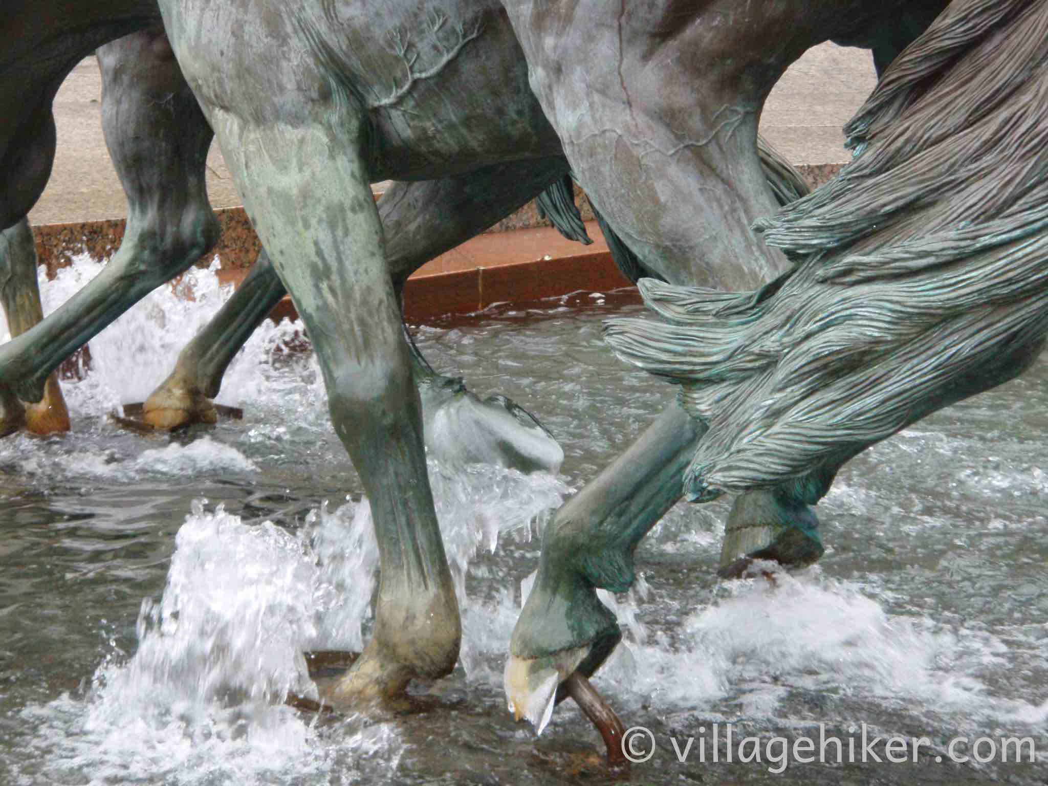 bronze mustangs splash through the fountain in a heavy rain.