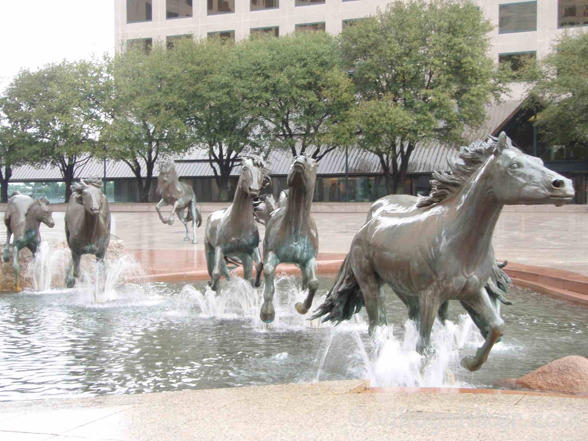 bronze mustangs splash through the fountain in a heavy rain.