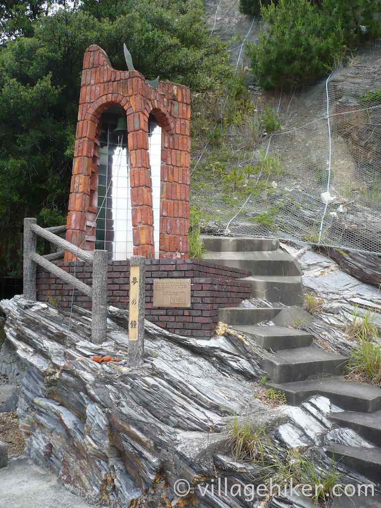 dream bell sits on small hill with steps leading up to it.