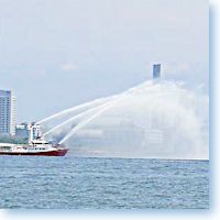 Tugboat spouting water arches on Sumida River welcomes cruise ship to Toyko Japan.