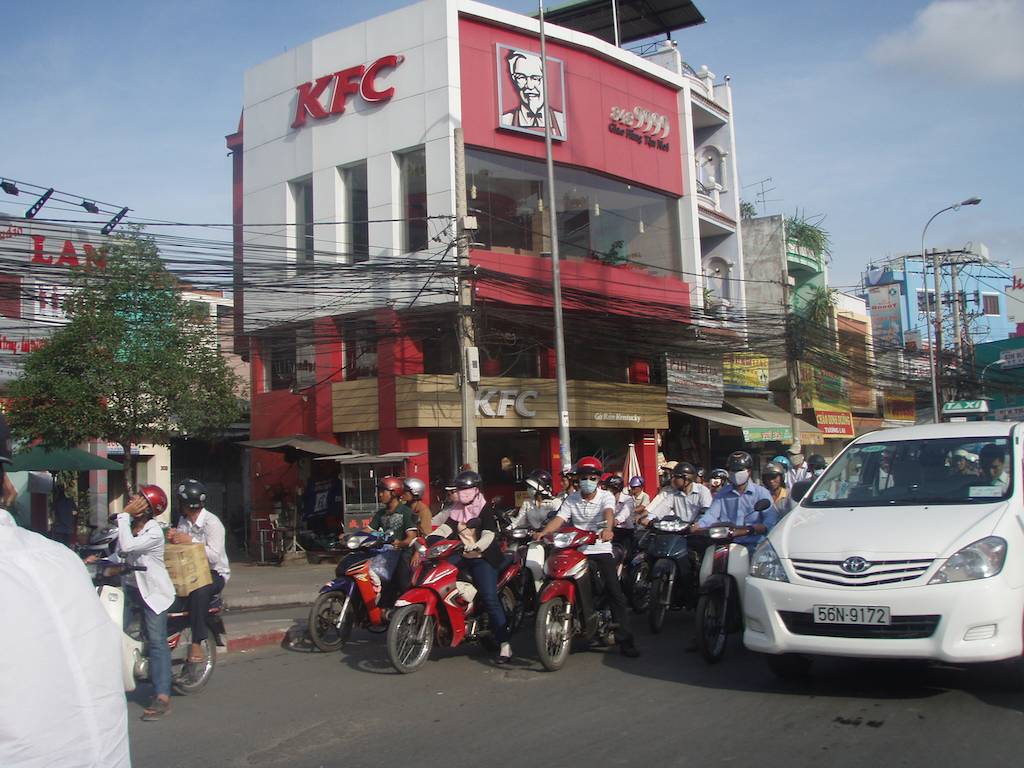 Motorbikes and Cars Wait at a Rare Light